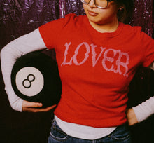 Load image into Gallery viewer, Person wearing a red shirt with 'LOVER' holding an eight-ball against a reflective purple curtain.
